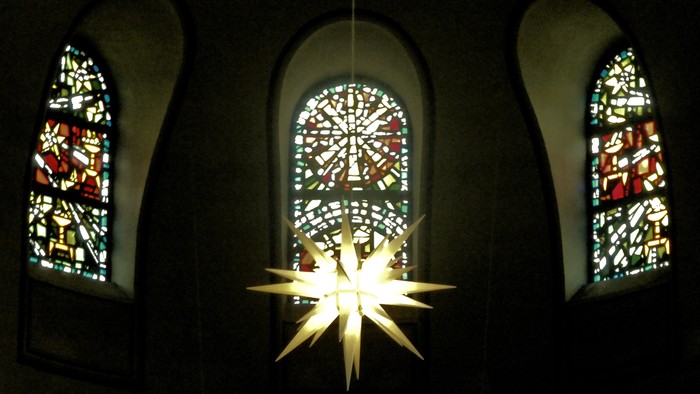 Drei bunte Kirchenfenster mit Sternleuchte davor