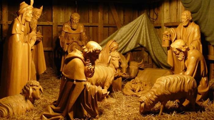 Eine Krippe mit Holzfiguren, darunter Maria, Josef und das Jesuskind in einer Stallenszene.