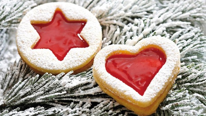 Zwei Plätzchen mit roter Marmelade auf Tannenzweigen