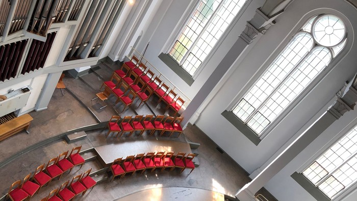 Großer Saal mit roten Stühlen und hohen Fenstern