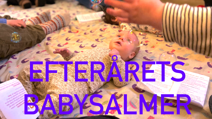 En baby ligger på en håndklæde med et voksemærke på armen, mens en person spiller på et instrument.