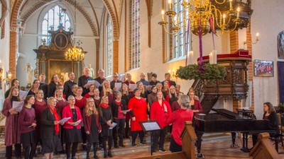 En kor sang i kirke med høje buevinduer og lysende kandlelygter.