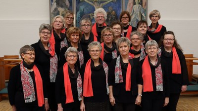 En gruppe kvinder i svart og rødt stander sammen i en kirke.