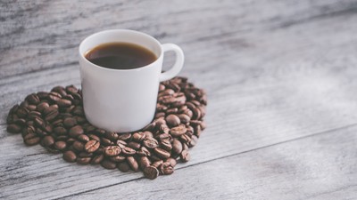 En lille hvid tekt med kaffe og kaffebønner på et træbord