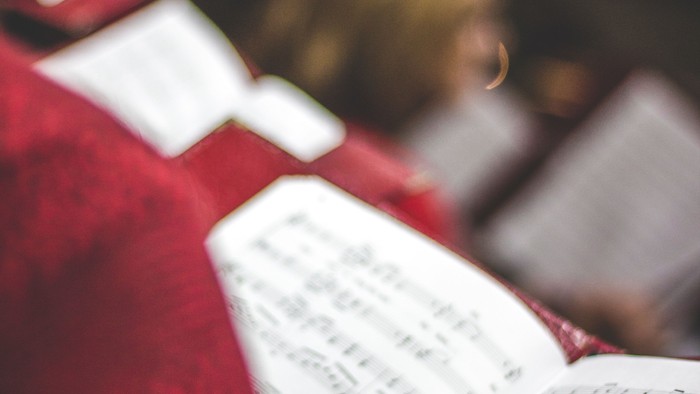 En gruppe af mennesker synger i kor, hver med en partitur i hånden.