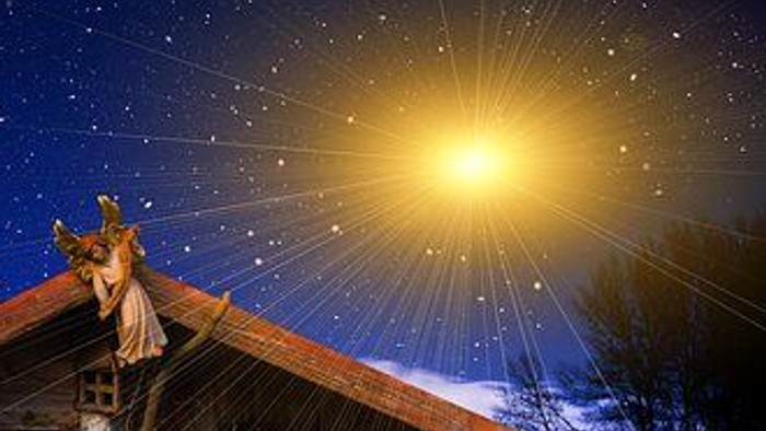 En julekreds med mange figurer foran en hytte under stjernerne