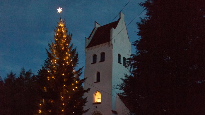En lysket julesejr med stjernen og en kirke mod nattehimmel