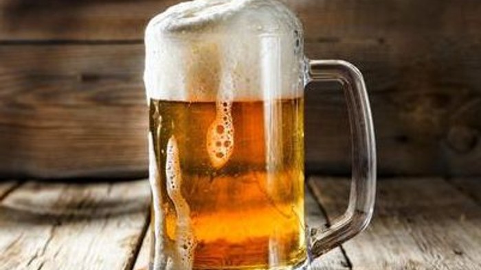 Ein Glas Bier steht auf einem Holztisch mit einem Messer daneben