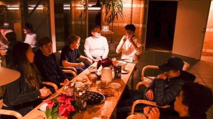 En gruppe af mennesker sidder om en lang bord og spiser sammen.