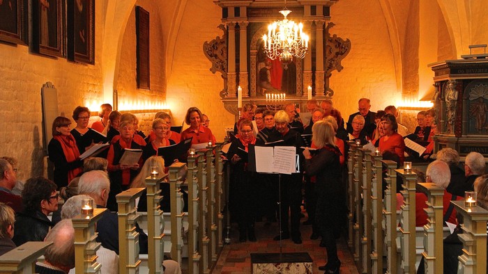 En kor sang i kirke med lysende kandlelyfter og publikum.