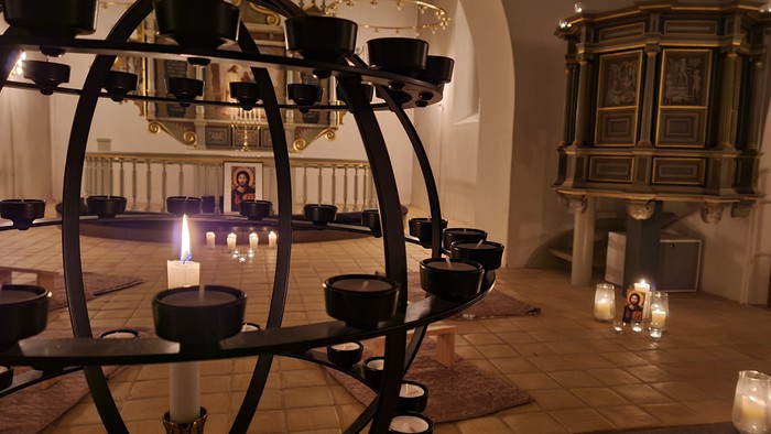 En kirke med mange lysestage og lysede lygter.