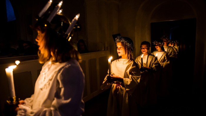 En gruppe børn i festlige kredenceremonier med lys.