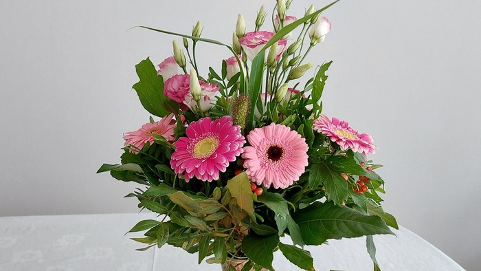 Ein Blumenstrauß in einer Vase auf einem Tisch mit einer Kerze und einer Karte