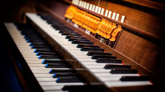Et orgel med sorte og hvide tangenter og en række knapper.