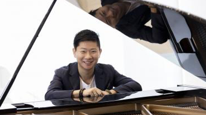 En mand spiller piano og smiler.