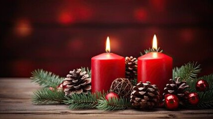 Zwei brennende rote Kerzen mit Tannenzweigen und Weihnachtskugeln