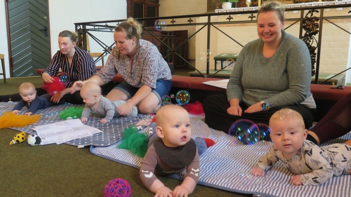 En gruppe voksne og børn spiller på boddemat i et stue.
