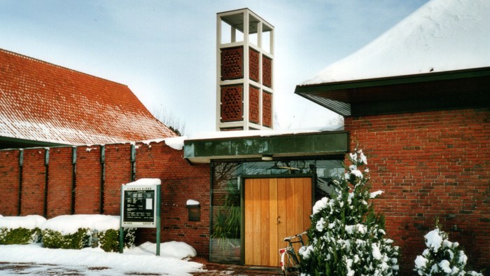 En snedækket kirke med tårn og trædør.