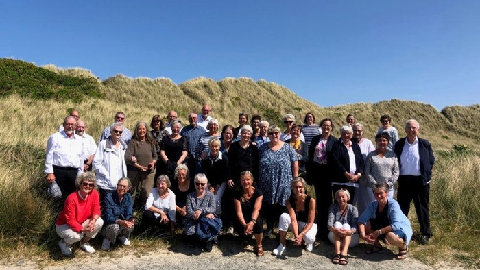 En stor gruppe af mennesker samlet på en sandstrand med en klækende bakgrund.