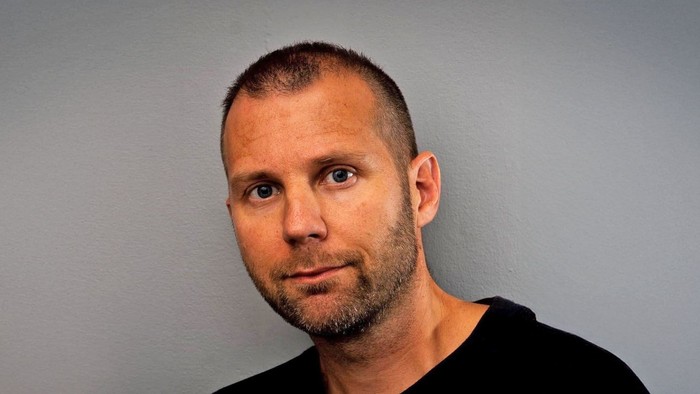 En bart og kahlueret mand i en sort trøje.