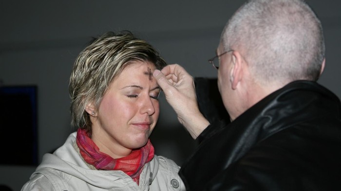 Frau mittleren Alters empfängt das Aschekreuz