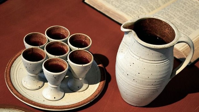 Auf einem Tisch stehen eine Kanne und mehrere Tassen mit Kaffee auf einem Untersetzer