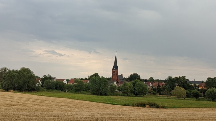 Landschaft mit Kirche und Feldern bei bewölktem Himmel