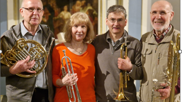 Vier Musiker posieren mit ihren Instrumenten in einem Saal