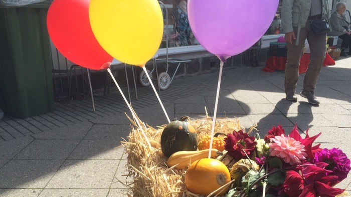En hestekøje med boller og blomster med tre balloner i røde, gule og lilla farver