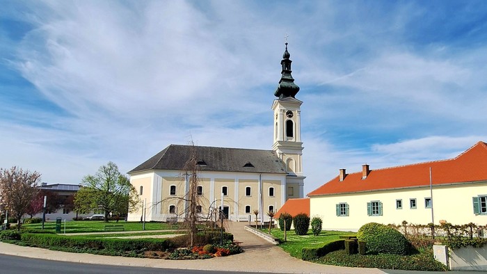 Weißes Gebäude mit hohem Turm und rotem Dach unter blauem Himmel