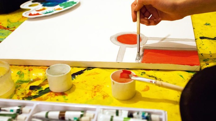 Kinder malen mit Pinseln und Farben auf Papier