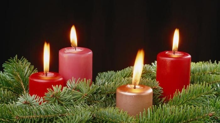 Vier brennende Kerzen auf Tannenzweigen