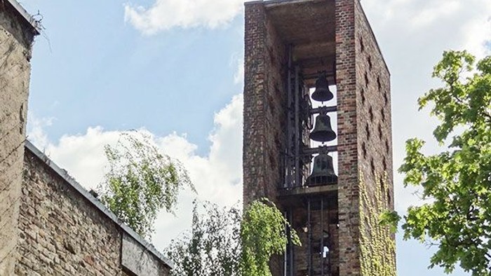 Ein hohes Ziegelgebäude mit Treppe, umgeben von grünen Bäumen und einem klaren blauen Himmel