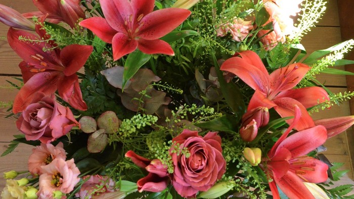 En blomsterstang med røde lilier og andre farvede blomster.
