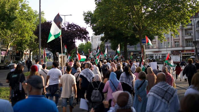 Eine Gruppe von Menschen marschiert mit Flaggen und Schildern durch eine Stadtstraße.