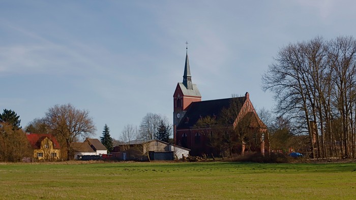 Kirche mit hohem Turm in ländlicher Umgebung