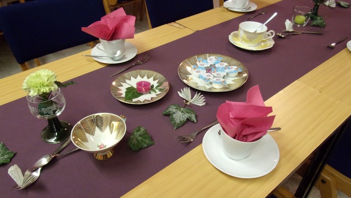 Gedeckte Tisch mit Teegeschirr, Blumen und Servietten