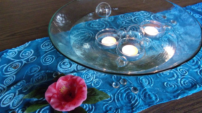 Blaues Tischtuch mit Glasplatte und Blume