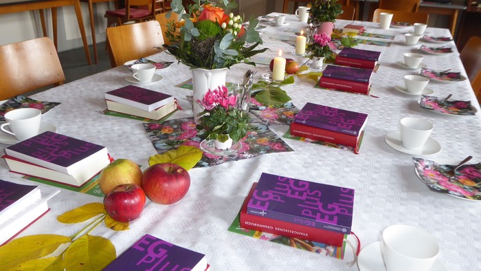 Tisch gedeckt mit Büchern, Teetassen, Blumen und Obst