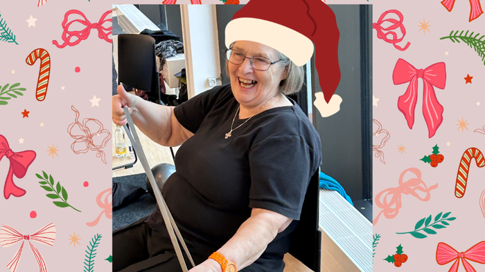 Kvinde med julemandshue, der holder en tablet og griner.