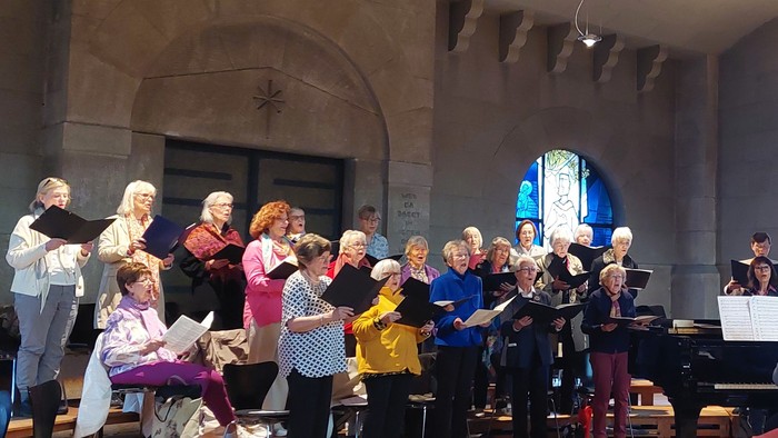 Ein Chor probt in einer Kirche, begleitet von einem Pianisten.