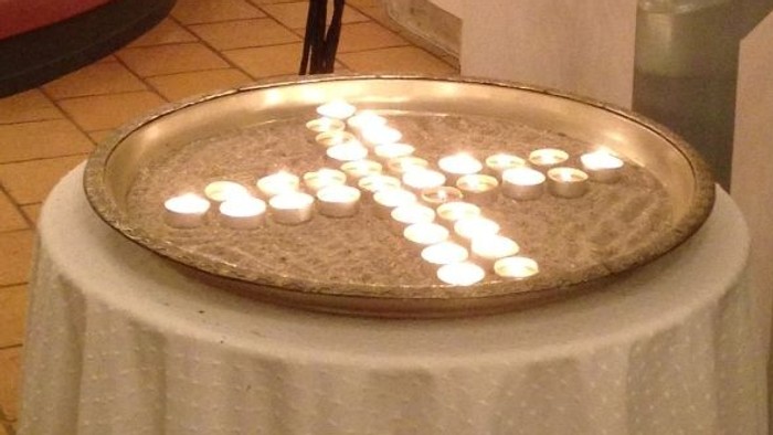 En lysestage i form af et træ med lysede lys og en rund lysestage med lysede lys på en bord.