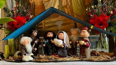 En julekreds med figurer foran en maleri.