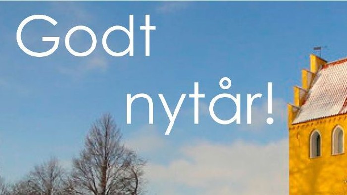Glad godt nytår! En smuk kirke med snø på taket under en klar blå himmel.