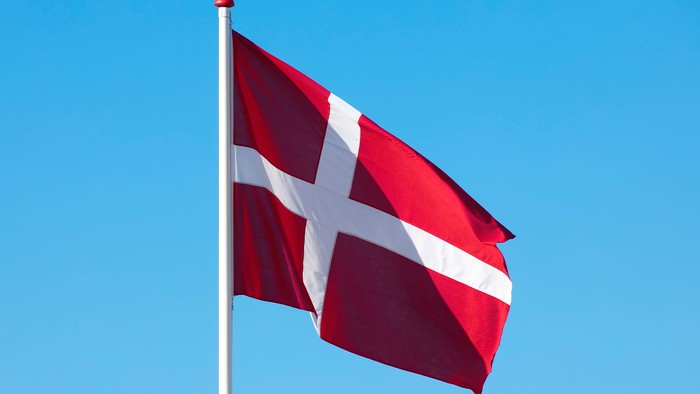 Det danske flag, kendt som Dannebrog, der vajer mod en klar blå himmel.