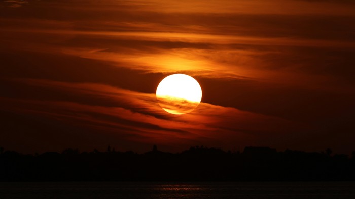 Solnedgang med livlige orange og gule nuancer, der kaster en varm glød over horisonten.