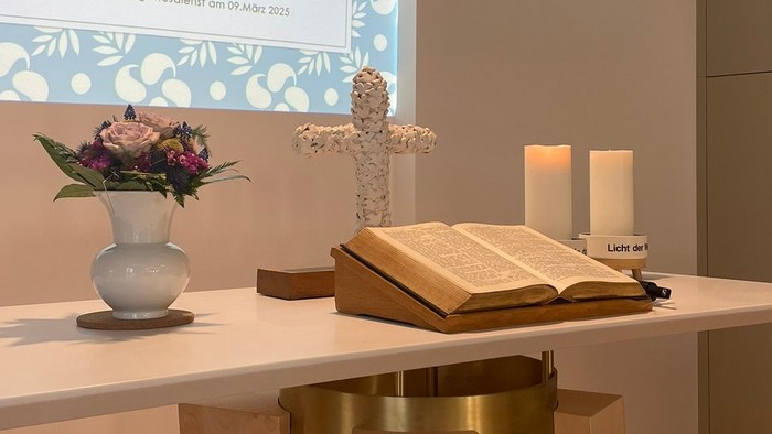Willkommensbereich mit Blumen, Kerzen und Bibel