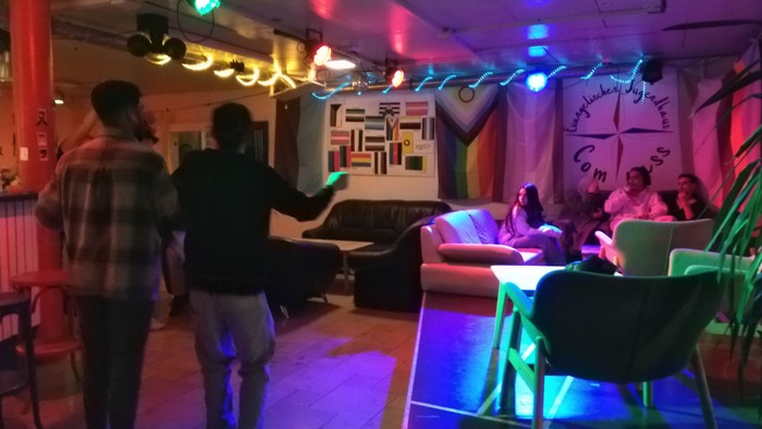 Lebendige Indoor-Lounge mit farbenfroher Beleuchtung, in der Menschen bewegungsgesteuerte Spiele spielen und sich unterhalten.