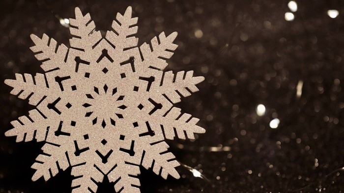 En snøfloke på mørk baggrund med glitrende effekter.