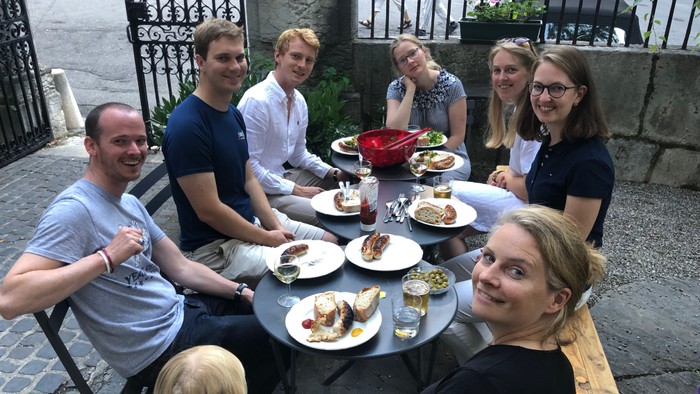 Eine Gruppe von Freunden sitzt bei einem gemeinsamen Essen im Freien.